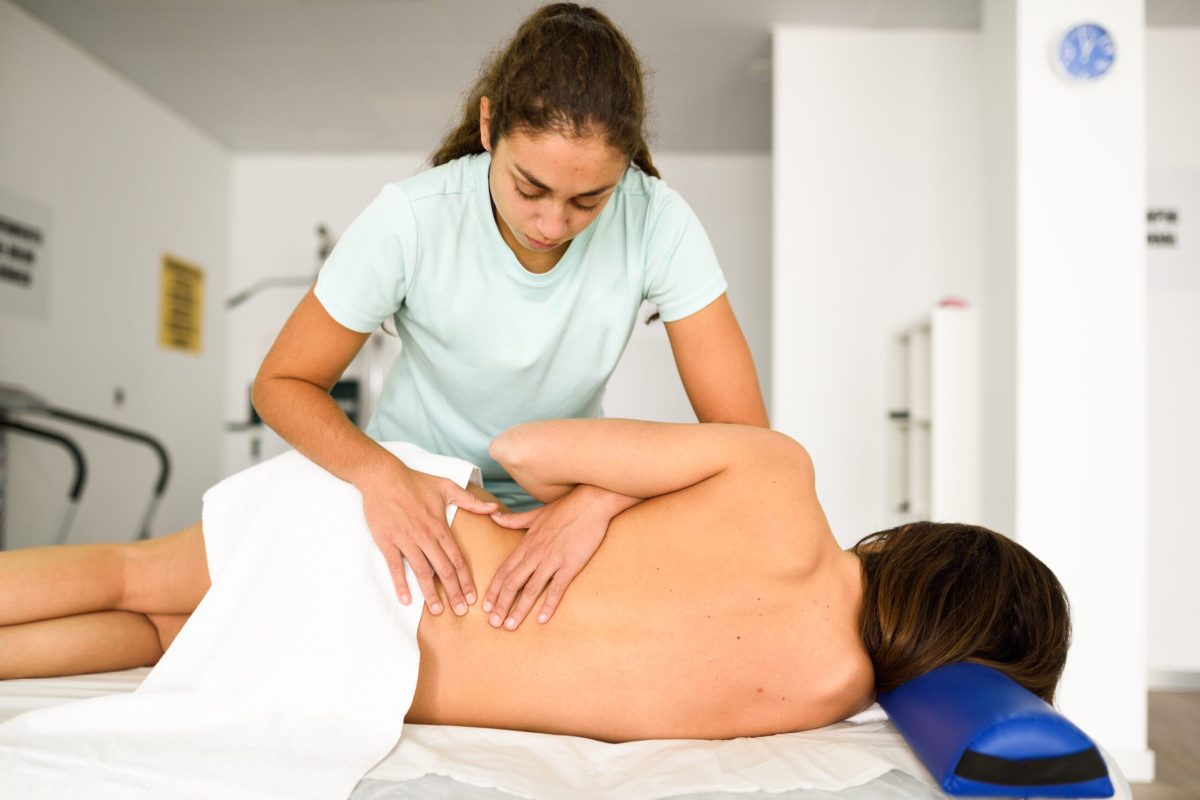 physiotherapist lumbar shoulder massage to brunette woman in hospital. Medical check at the shoulder